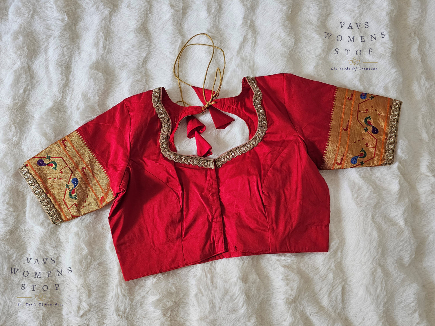 Red blouse with intricate gold and multicolor patterns on a textured white background